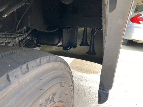 2015 Ford F-550 - Close-up view of air horns installed on a heavy-duty vehicle, with a tire and another car in the background.
