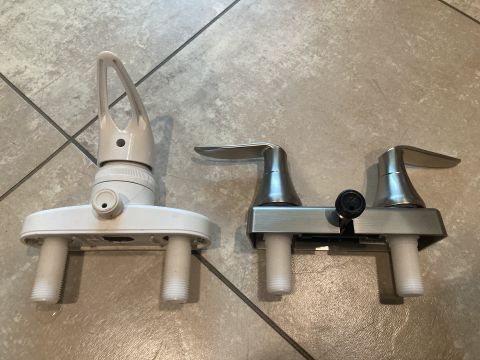 2015 Ford F-550 - Two shower faucets are shown side-by-side on a tiled floor. The faucet on the left is white with a single lever, while the one on the right…