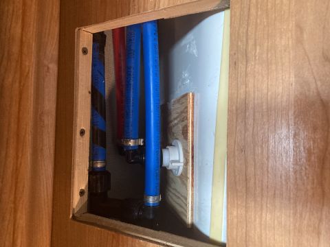 2015 Ford F-550 - Close-up view of the plumbing lines and access panel within an RV's interior cabinetry.