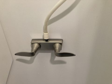 2015 Ford F-550 - Close-up of a brushed nickel shower faucet with a flexible white hose.