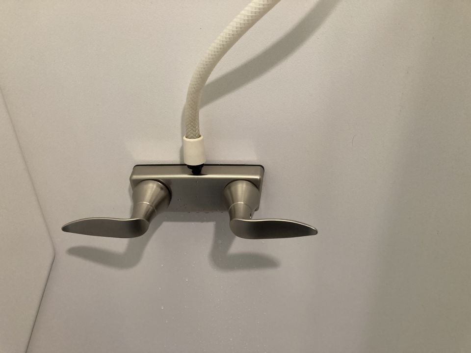 Shower faucet with two handles and a white hose attached