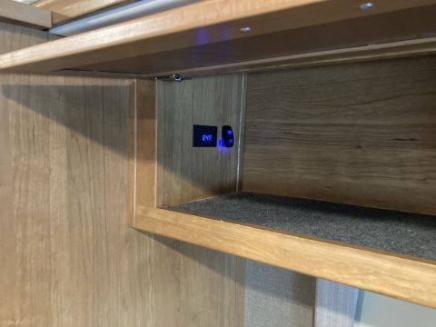 2015 Ford F-550 - A digital thermometer displays 84F next to a lit blue switch, mounted within a wooden interior compartment.
