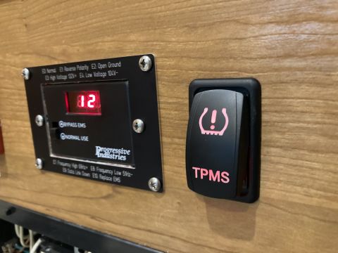 2015 Ford F-550 - Close-up of a TPMS indicator light and a Progressive Industries control panel with a digital display showing '12'.