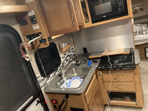 2015 Ford F-550 - Interior view of an RV kitchen showing a sink, stovetop, and microwave, with some electrical components visible.