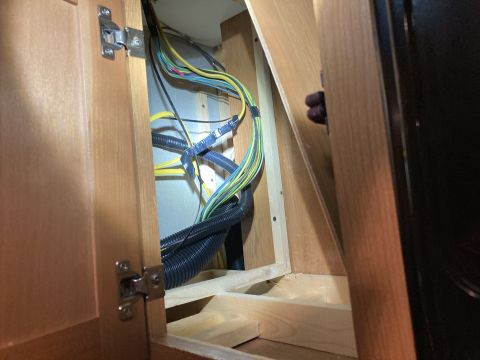 2015 Ford F-550 - Close-up of complex wiring within a wooden compartment, showing various colored cables and protective conduits.