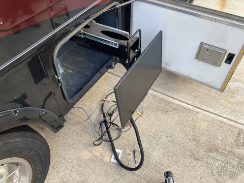 2015 Ford F-550 - A black compartment on a vehicle is open, revealing a slide-out tray and a TV with its cables disconnected.