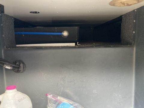 2015 Ford F-550 - A view inside a compartment showing plumbing and storage, with a Supermotors.net logo at the bottom right.