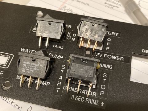 2015 Ford F-550 - A close-up view of a monitor panel four toggle switches for various functions including water pump and generator control.