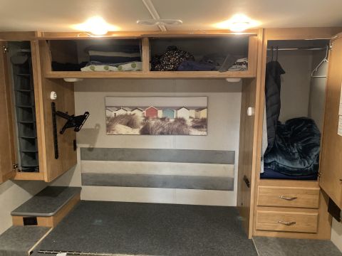 2015 Ford F-550 - The interior of an RV shows a bed area with storage above and to the side, and a closet with clothing.