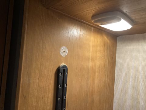 2015 Ford F-550 - The interior of a cabinet shows a light fixture and a mounting bracket on a wood-paneled wall.