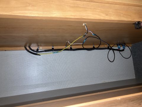 2015 Ford F-550 - Wiring harness with black loom and yellow wire secured with zip ties under wooden paneling.