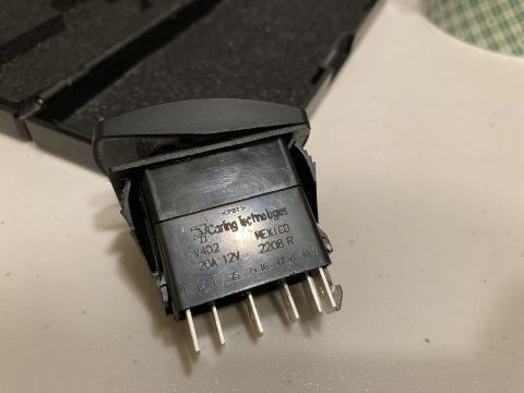 2015 Ford F-550 - Close-up of a black automotive switch, marked with manufacturer and electrical ratings.