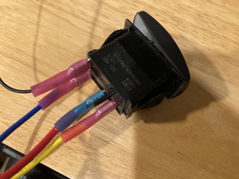 2015 Ford F-550 - A close-up view of a Carling Technologies switch with wires connected, resting on a wooden surface.