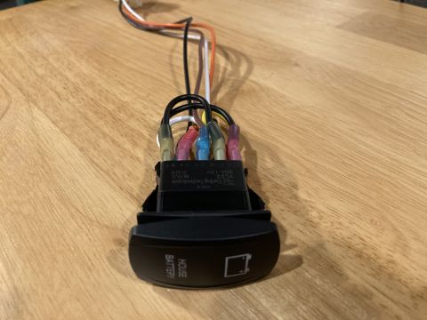 2015 Ford F-550 - A close-up view of a house battery switch with multiple wires attached, resting on a wooden table.