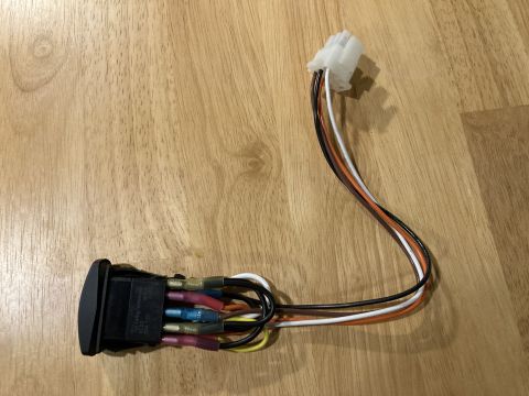 2015 Ford F-550 - A close-up view of a wiring harness connected to a switch, resting on a wooden background.