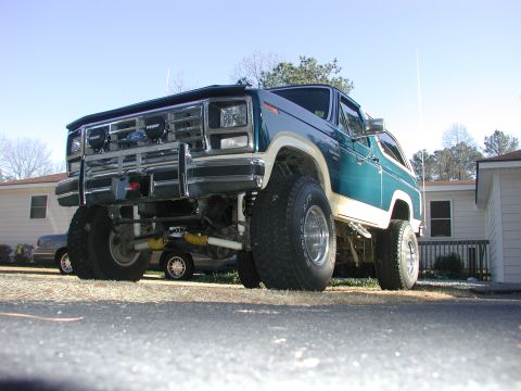 1985 Ford Bronco - This lifted Ford Bronco has a two-tone paint scheme and is parked on a paved surface.