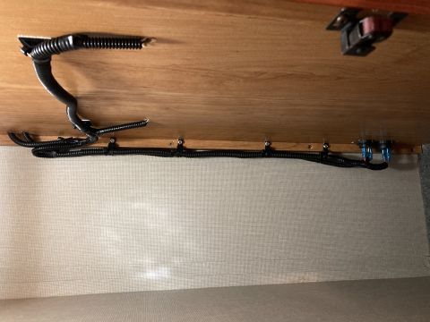 2015 Ford F-550 - A close-up view shows a wiring harness and conduit secured to a wooden surface, with blue electrical connectors visible at the end.