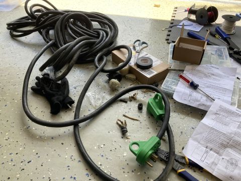 2015 Ford F-550 - Electrical supplies including a heavy gauge extension cord, gloves, tools, and instructions are laid out on a garage floor.