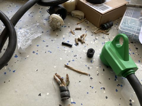 2015 Ford F-550 - Various electrical components, including damaged cords and adapters, are spread across a garage floor.