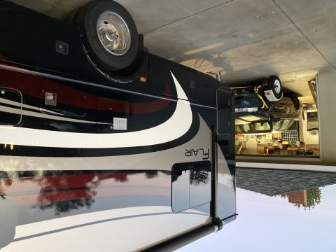 2015 Ford F-550 - An RV motorhome with 'Flair' branding is parked in a garage, with a car visible behind it.