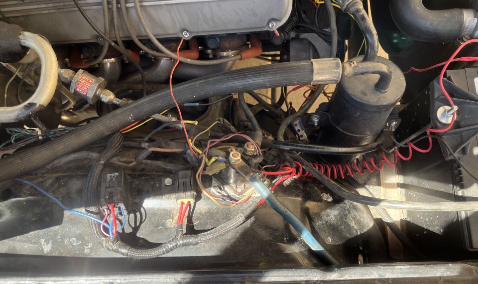 Engine bay with lots of wires, hoses, and engine parts. Some text on a filter reads 'SUPERMOTORS'