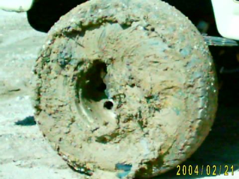 1985 Ford Bronco - Mud-caked tire and wheel from a vehicle, likely after off-roading.