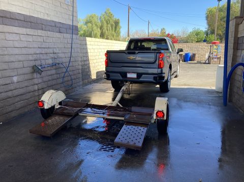 2015 Ford F-550 - A modern pickup truck is hitched to a trailer at a self-service car wash bay.