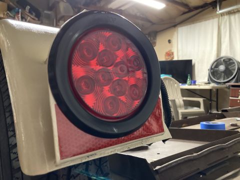 2015 Ford F-550 - Close-up of a round red LED trailer tail light assembly, a black bezel and a red reflector panel.