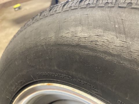 2015 Ford F-550 - Close-up of a worn tire showing significant cracking on the sidewall, indicating age and potential damage.
