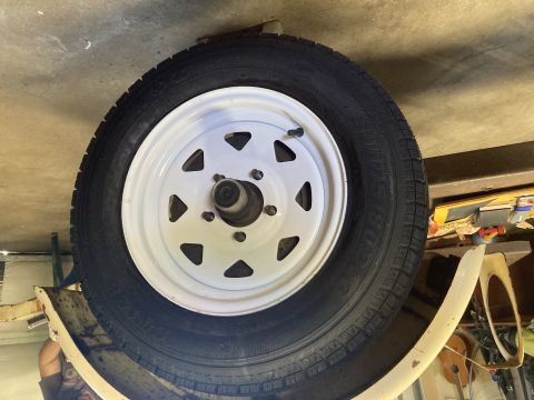 2015 Ford F-550 - A spare tire is mounted on a white rim, attached to a trailer's frame.