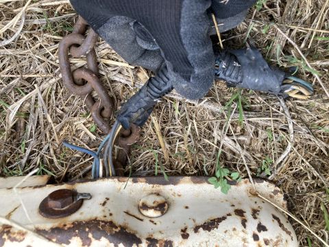 2015 Ford F-550 - A gloved hand holds a rusty chain near damaged wiring, with exposed wires visible on the ground.