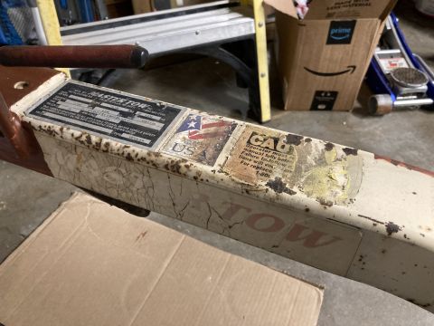 2015 Ford F-550 - A close-up view of a tow dolly's metal frame, showing various warning labels and the 'TOW' branding.