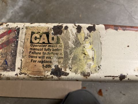 2015 Ford F-550 - A close-up view of a caution sticker with faded text and peeling edges on a weathered metal surface.