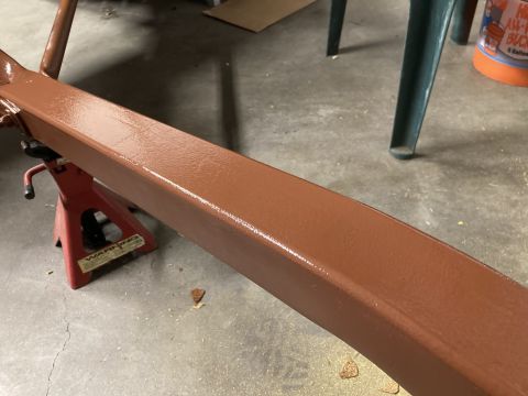 2015 Ford F-550 - A metal beam, freshly painted brown, is supported by jack stands in a workshop setting.