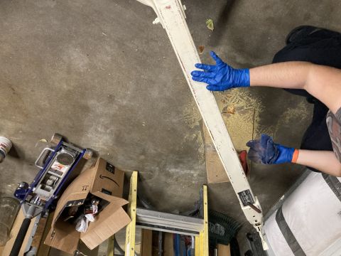 2015 Ford F-550 - A person in blue gloves cleans a long, white vehicle component in a garage setting, with tools and boxes visible.
