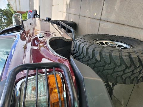 1996 Ford Bronco - A maroon SUV is parked next to a large off-road spare tire, with a Supermotors watermark visible.