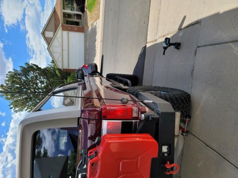 1996 Ford Bronco - Rear view of a maroon Jeep Wrangler with a white hardtop, spare tire, and auxiliary fuel cans.