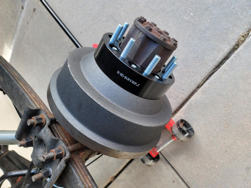 Black wheel spacer on drum brake assembly with visible text '2-8X6.5-8/126-15'