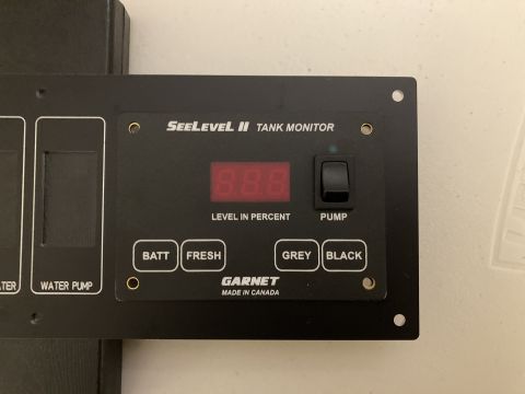 2015 Ford F-550 - A close-up view of a Garnet SeeLevel II tank monitor panel, indicating water levels and pump status.