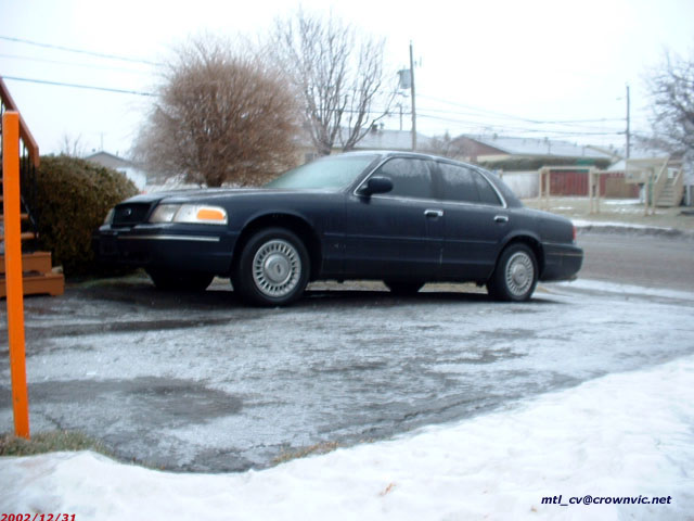 Dark Ford Crown Victoria parked on an icy snowy lot in a residential area, dated 2002/12/31