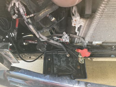 2015 Ford F-550 - Close-up view of the battery tray and associated wiring harness, with a portion of the vehicle's radiator in the background.
