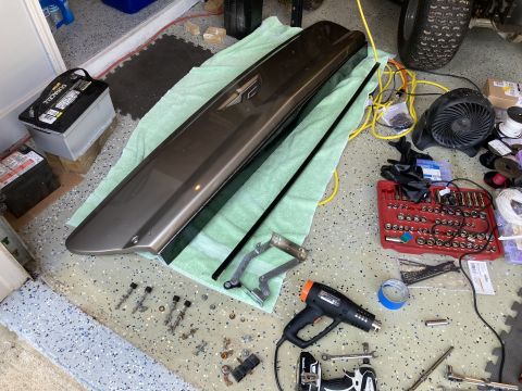 2015 Ford F-550 - Various tools and a car door trim piece are spread across a garage floor, suggesting a repair or installation process.