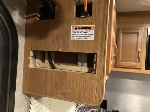 2015 Ford F-550 - This is a close-up of an RV's interior cabinet panel, a warning sticker and exposed wiring behind a cutout.