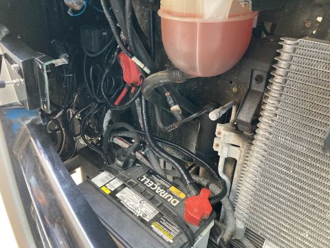 2015 Ford F-550 - Close-up view of a Duracell battery and various engine bay components, including wiring and part of the radiator.