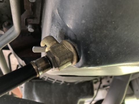 2015 Ford F-550 - Close-up view of an oil drain valve connected to a hose, likely part of an engine maintenance procedure.