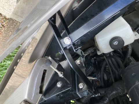 2015 Ford F-550 - This image shows a close-up view of a vehicle's hood bracket assembly and a fluid reservoir.