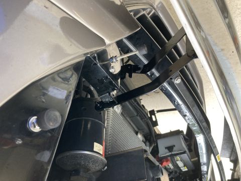 2015 Ford F-550 - Close-up view of hood brackets and a component under the front of a vehicle.