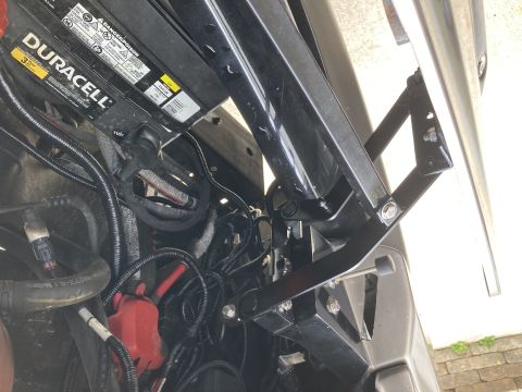 2015 Ford F-550 - Close-up of a black hood bracket and a Duracell battery in the engine compartment.