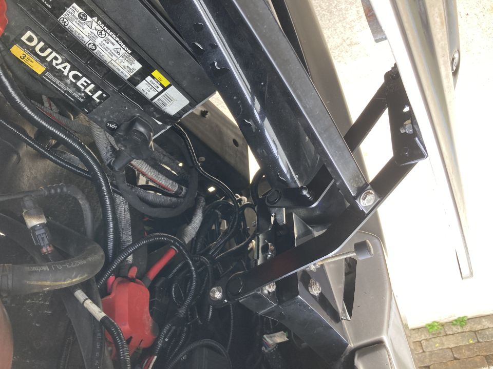 Black hood bracket near Duracell battery in engine bay