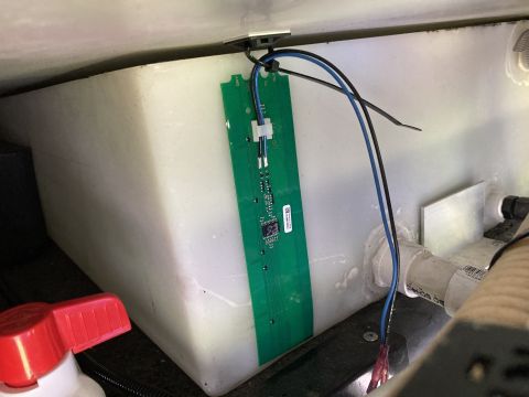 2015 Ford F-550 - A green circuit board is mounted to a white tank with visible wiring and plumbing components.